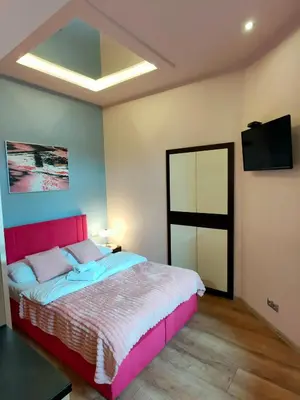a bedroom with a pink bed and a flat screen tv at Mirror Pink Studio Apartment in Kraków