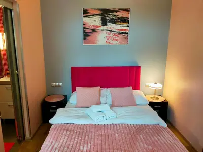 a bedroom with a large bed with a red headboard at Mirror Pink Studio Apartment in Kraków