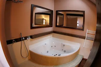 a large bath tub in a bathroom with two mirrors at Krakow Jacuzzi Apartment in Kraków