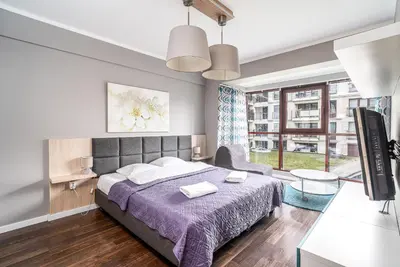 a bedroom with a bed and a large window at RentPlanet - Apartamenty Przemysłowa in Kraków