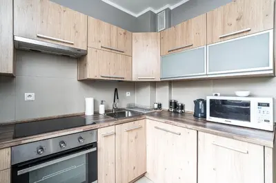 a kitchen with wooden cabinets and a microwave at RentPlanet - Apartamenty Przemysłowa in Kraków