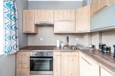 a kitchen with wooden cabinets and a sink at RentPlanet - Apartamenty Przemysłowa in Kraków