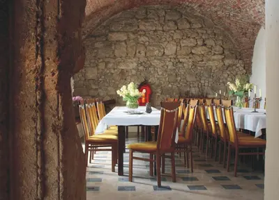 a dining room with a table and chairs and a stone wall at Zamek Korzkiew in Korzkiew