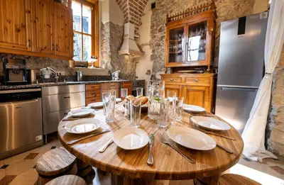 a kitchen with a wooden table with plates and silver appliances at Zamek Korzkiew in Korzkiew