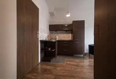 a kitchen with brown cabinets and a wooden floor at Przytulny apartament Kos w sercu Krakowa in Kraków