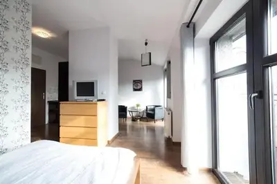 a bedroom with a bed and a desk with a television at Przytulny apartament Kos w sercu Krakowa in Kraków