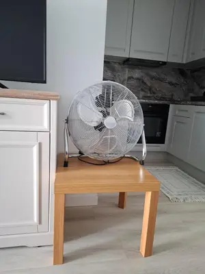 a white fan sitting on top of a wooden table at Bagry Rooms2 - Apartament z sypialnią i miejscem postojowym in Kraków