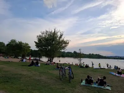 a group of people sitting on the grass near a lake at Bagry Rooms2 - Apartament z sypialnią i miejscem postojowym in Kraków