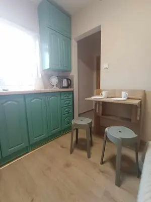 a kitchen with green cabinets and a table and two stools at Blisko Energylandii in Zator