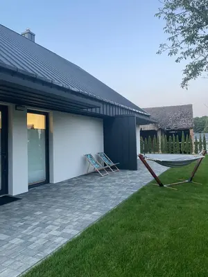 a patio with two chairs and a hammock in front of a house at Apartamenty 91 in Spytkowice