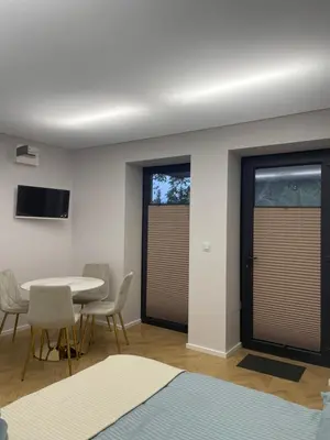 a room with a table and chairs and windows at Apartamenty 91 in Spytkowice