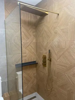 a shower in a bathroom with a wooden wall at Apartamenty 91 in Spytkowice