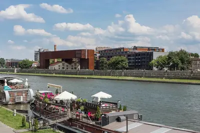 a boat with tables and umbrellas on a river at Apartament z widokiem na Wisłę in Kraków