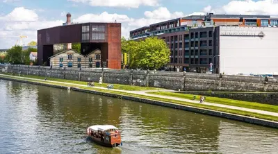 a boat traveling down a river in a city at Apartament z widokiem na Wisłę in Kraków