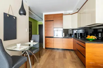 a kitchen with wooden cabinets and a glass table at Apartament z widokiem na Wisłę in Kraków