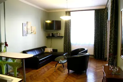a living room with a black leather couch and a table at Apartamenty Astur in Kraków