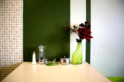 a green vase with flowers in it on a table at Apartamenty Astur in Kraków