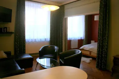 a living room with chairs and a table and a bed at Apartamenty Astur in Kraków
