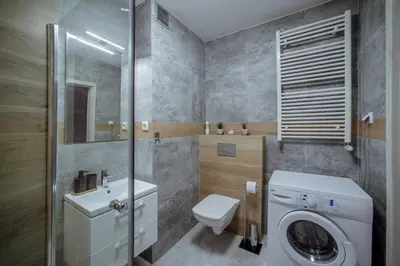 a bathroom with a toilet sink and a washing machine at Apartament Jana 14 z garażem podziemnym in Bochnia