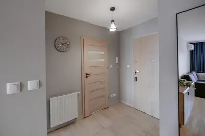 a hallway with a door and a clock on the wall at Apartament Jana 14 z garażem podziemnym in Bochnia
