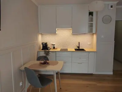 a kitchen with white cabinets and a small table at Bagry Lake Apartment in Kraków