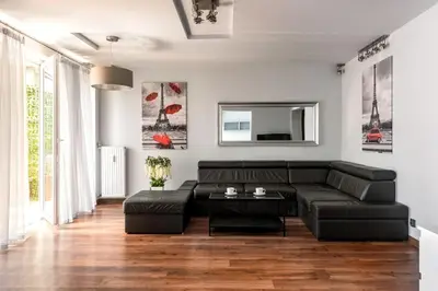 a living room with a black leather couch at Apartament PARYSKI 4 pokoje 90m2 2 poziomy Ogród Oranżeria in Kraków
