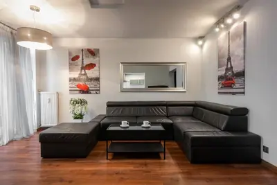 a living room with a black leather couch and a table at Apartament PARYSKI 4 pokoje 90m2 2 poziomy Ogród Oranżeria in Kraków