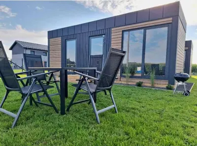 two chairs and a table in front of a house at Domki w Zatorze in Zator