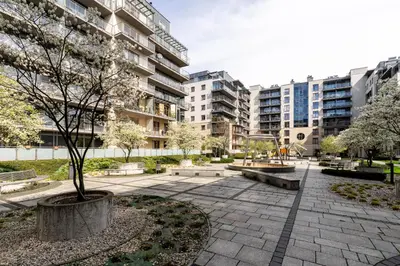 a park with benches and a tree and buildings at Glossy Apart G30 in Kraków