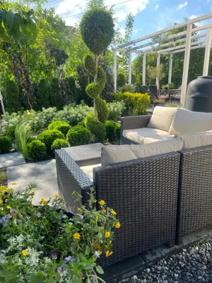 a patio with wicker chairs and flowers in a garden at Dziupla in Wygiełzów