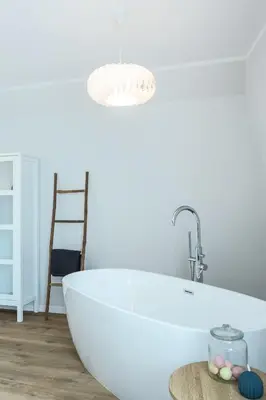 a white bath tub in a bathroom with a chair at Heima in Zawoja