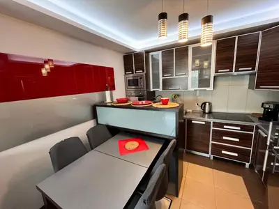 a kitchen with red cabinets and a table with a red napkin at Cracow Stay Premium Apartments FREE PARKING - 3 x ROOM - 3 x AIRCONDITION in Kraków