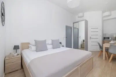a white bedroom with a large bed and a desk at Studio apartment with balcony - Starowiślna 41 in Kraków
