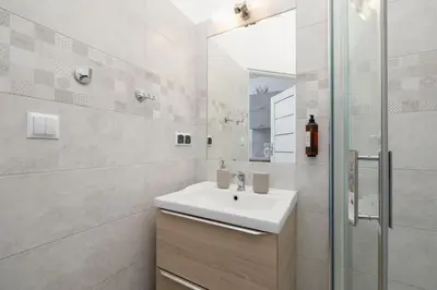 a white bathroom with a sink and a mirror at Studio apartment with balcony - Starowiślna 41 in Kraków