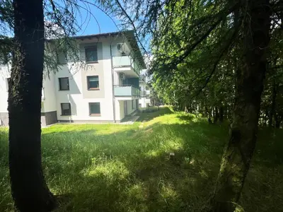 a large white building with trees in the foreground at Apartament Podedworze in Bochnia