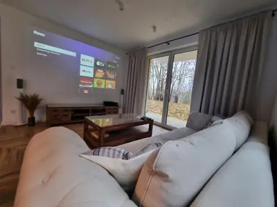a living room with a white couch and a large screen at Apartament Podedworze in Bochnia