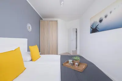 a bedroom with a white bed with a wooden cabinet at Apartament Rodzinny z 2 Sypialniami & Klimatyzacja by Noclegi Renters in Kraków