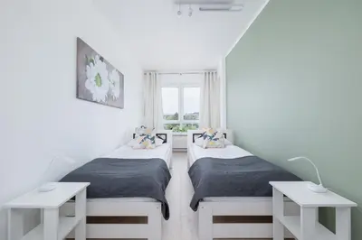 two beds in a white room with a window at Apartament Rodzinny z 2 Sypialniami & Klimatyzacja by Noclegi Renters in Kraków