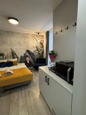 a kitchen and living room with a bed and a microwave at Wow! Paradise Aparthotel in Kraków