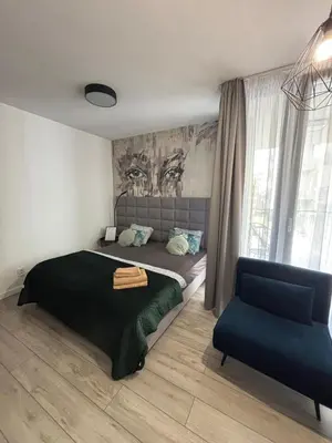 a bedroom with a bed and a blue chair at Wow! Paradise Aparthotel in Kraków