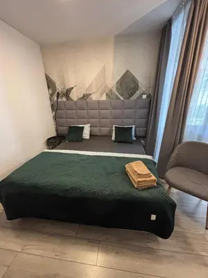 a bedroom with a bed with a headboard and a chair at Wow! Paradise Aparthotel in Kraków