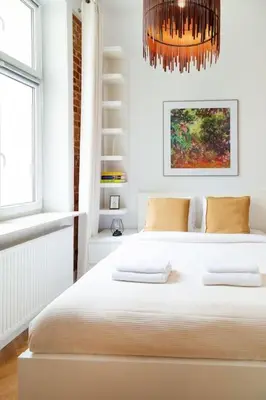 a white bedroom with a bed and a chandelier at Househost Apt - Krowoderska 55 in Kraków