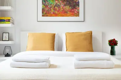 a white bed with three pillows and a painting at Househost Apt - Krowoderska 55 in Kraków