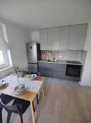 a kitchen with a wooden table and a dining room at New Apartment Macedońska in Kraków