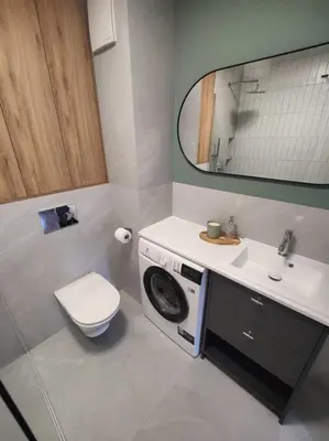 a bathroom with a washing machine under a sink at New Apartment Macedońska in Kraków