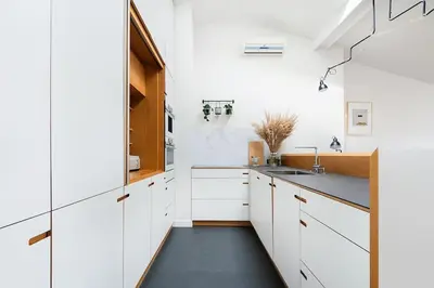 a kitchen with white cabinets and a black floor at Penthouse - Heart of Cracow - Balcony - AC in Kraków