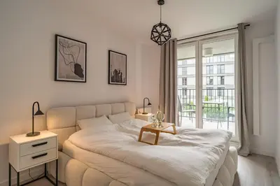 a white bedroom with a bed and a window at Grzegórzki Apt - Balcony, AC, Shops&Tram nearby - by Rentujemy in Kraków