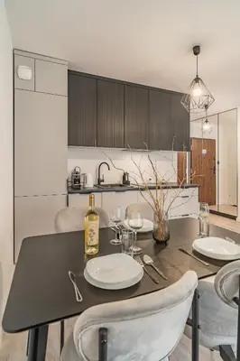 a kitchen with a table with plates and wine glasses at Grzegórzki Apt - Balcony, AC, Shops&Tram nearby - by Rentujemy in Kraków