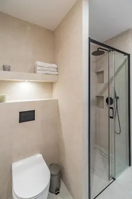 a bathroom with a toilet and a glass shower at Grzegórzki Apt - Balcony, AC, Shops&Tram nearby - by Rentujemy in Kraków