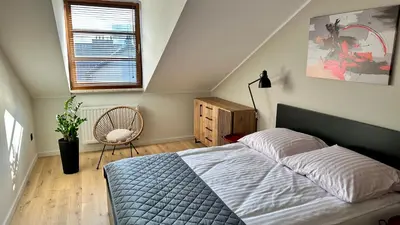 a bedroom with a bed and a window and a chair at Apartament Widna 3 in Kraków